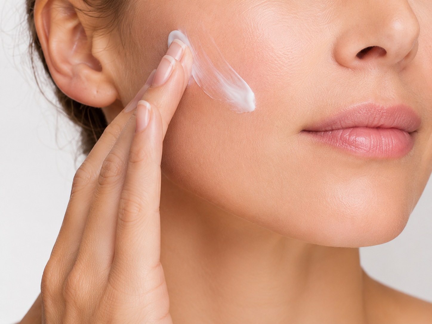 Woman applying skincare cream to her cheek